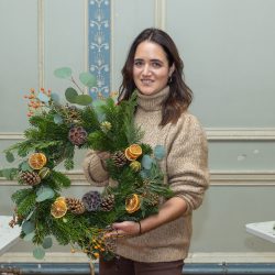 Lady holding a Christmas wreath made at a workshop run by Just So Flowers.