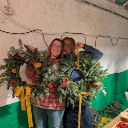 Two ladies holding their Christmas wreaths that they made at a workshop run by Just So Flowers