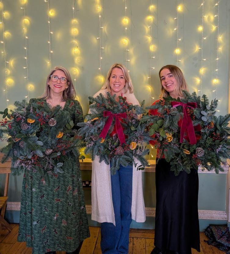 Three ladies with their Cristmas wreaths made at a wreath workshop run by Just So Flowers
